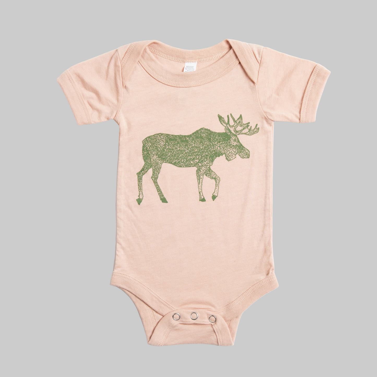 Bird and Buffalo’s baby onesie in pink with a green moose design, made locally in Jackson Hole, WY