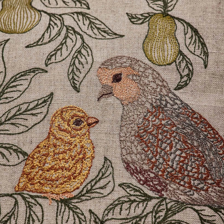 Coral and Tusk's "Partridge in A Pear Tree" embroidered linen pillow featuring a design of four partridges plus a chick perched in pear tree branches