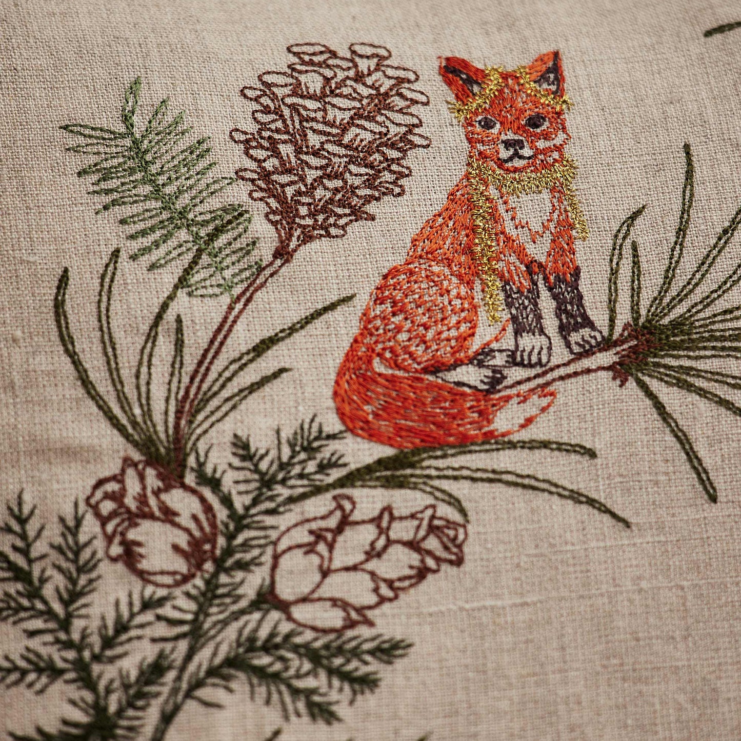 Coral and Tusks “Tree Trimmers Wreath” embroidered linen pillow featuring animal friends ushering in the holidays by decorating an evergreen wreath, measures 20” x 20”