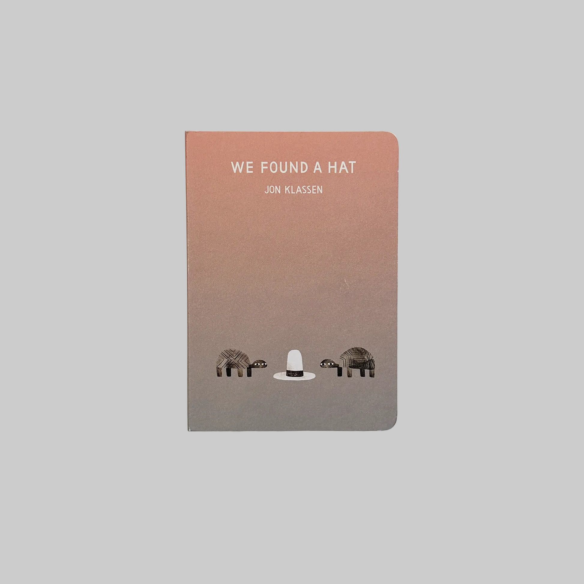 Children's book cover for 'We Found A Hat' by Jon Klassen featuring an illustration of two turtles and a hat.