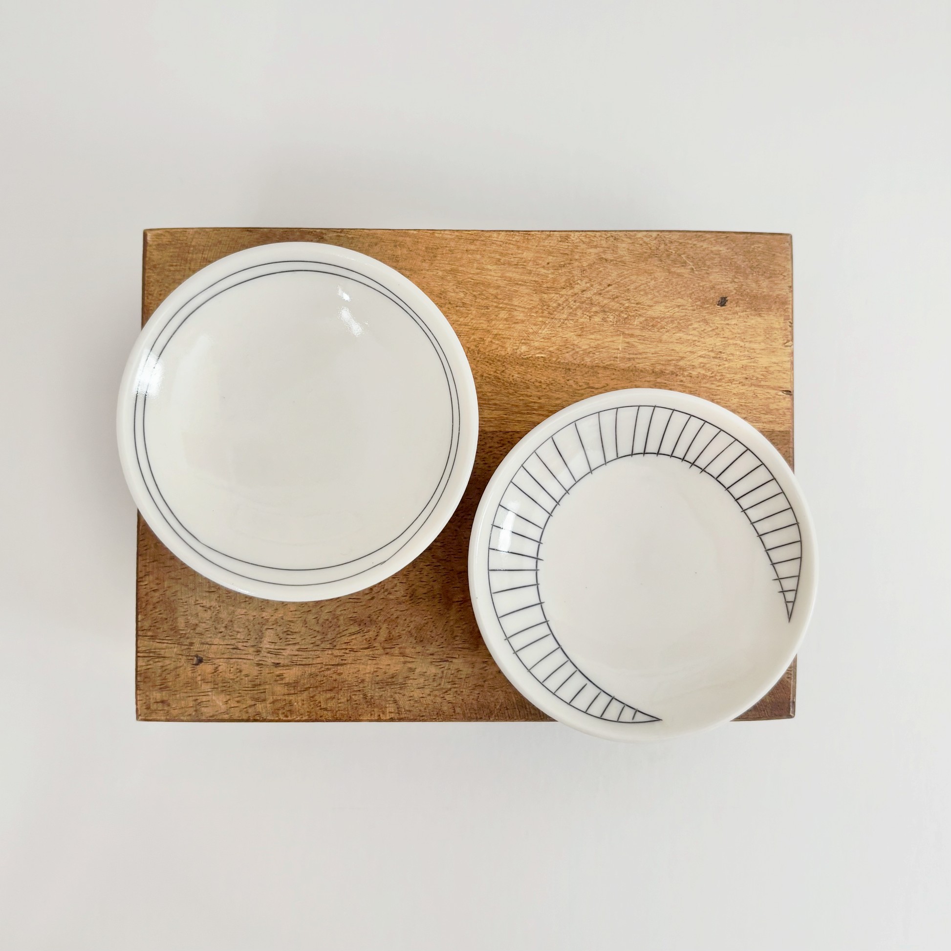 Two white ceramic dishes with black line designs made by Jenny Dowd
