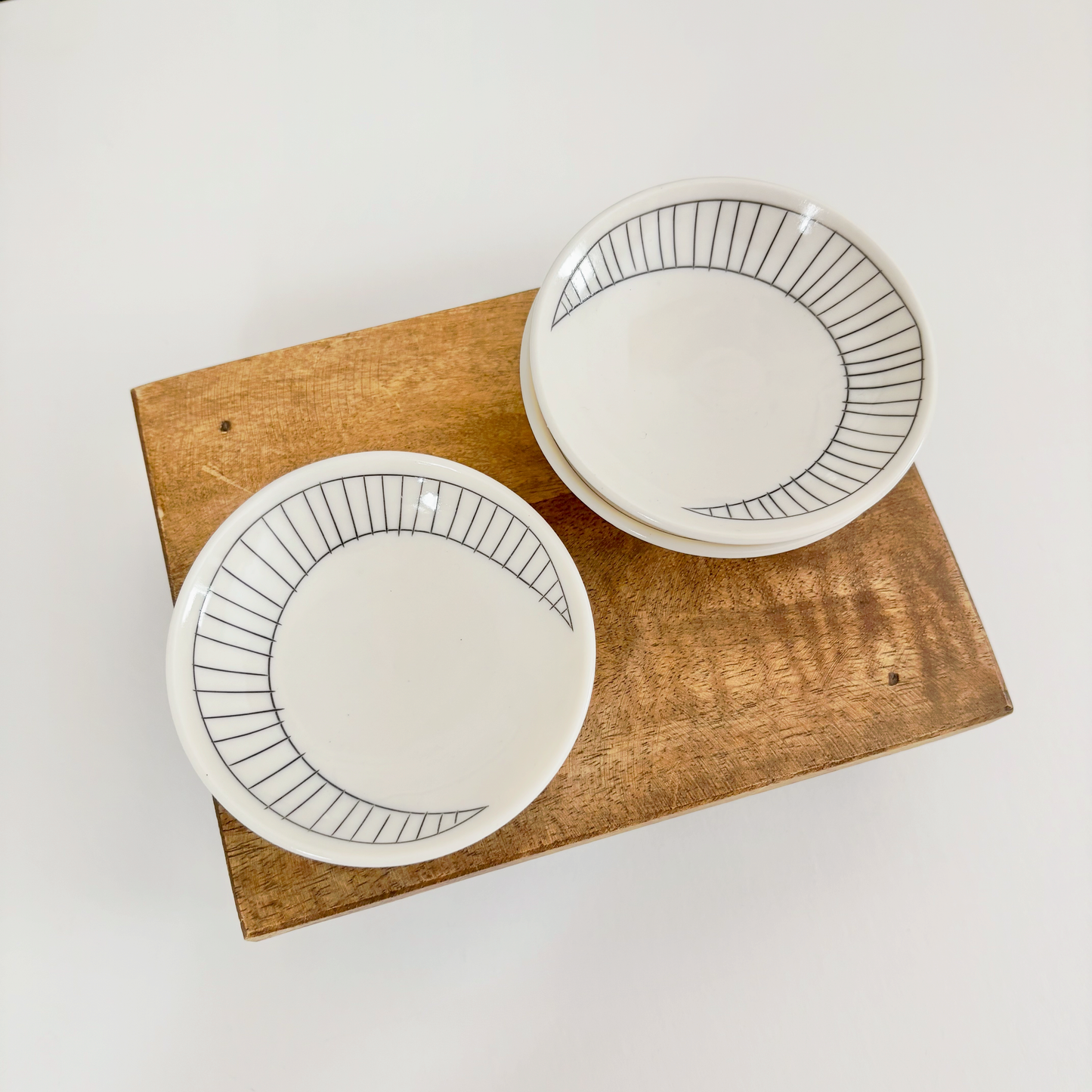 Two white ceramic dishes with black crescent line designs made by Jenny Dowd