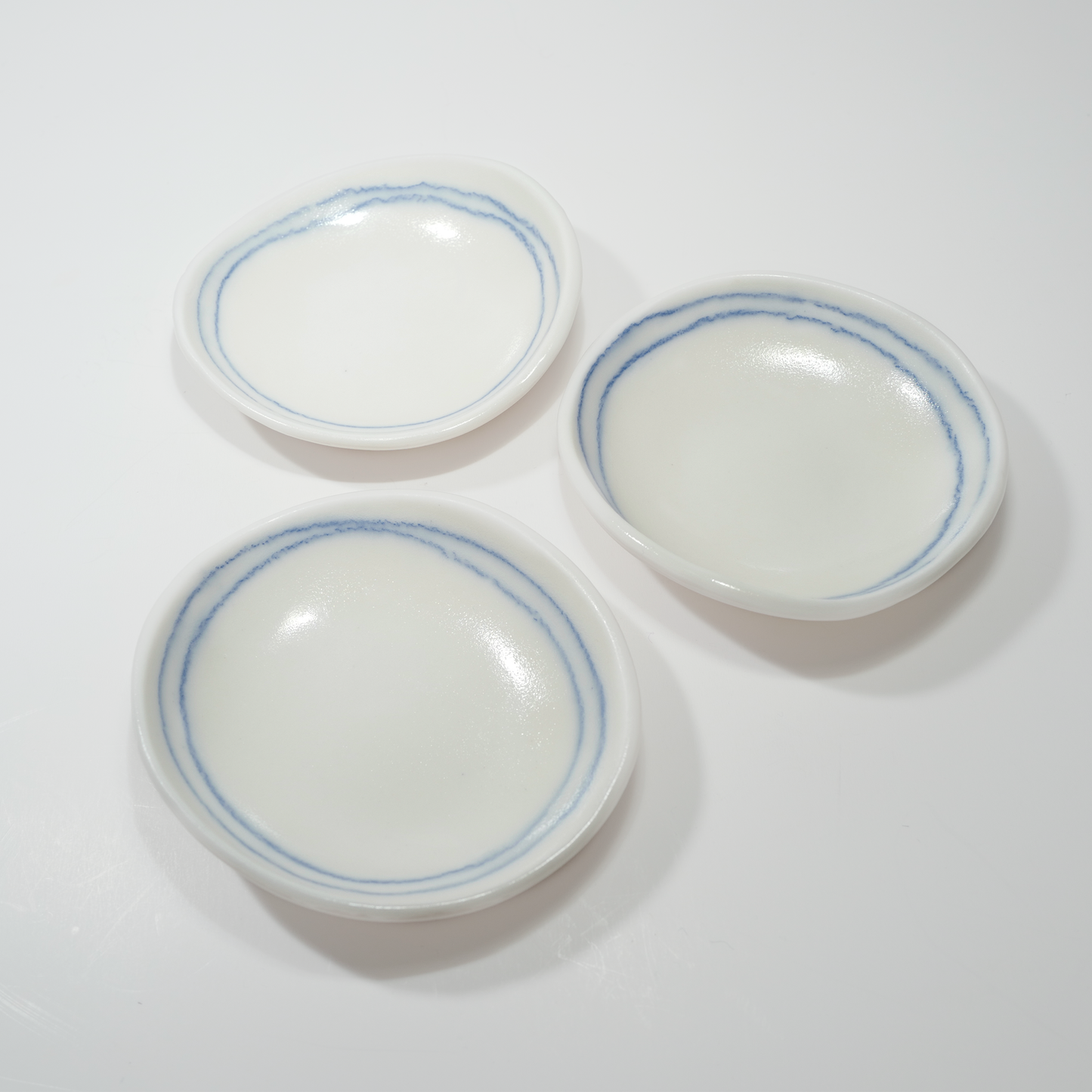 Three white ceramic dishes with blue line designs, made by Jenny Dowd