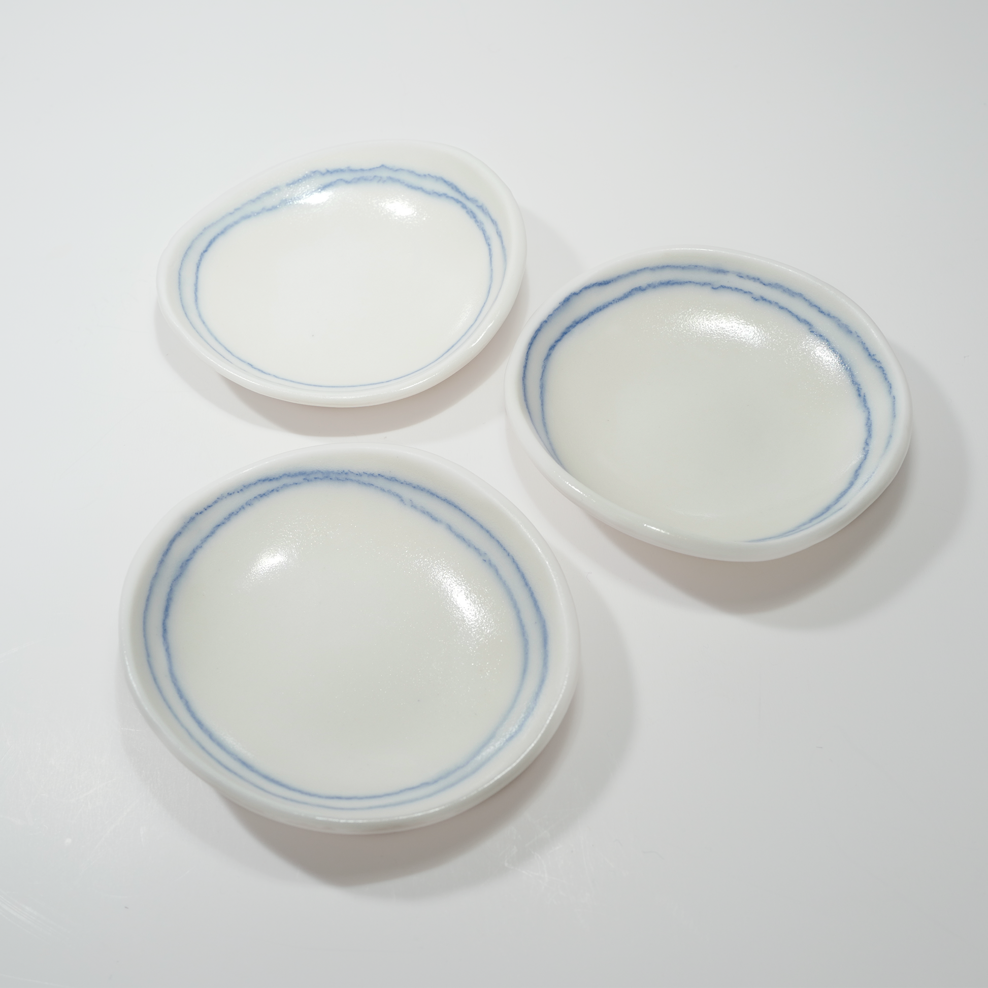Three white ceramic dishes with blue line designs, made by Jenny Dowd