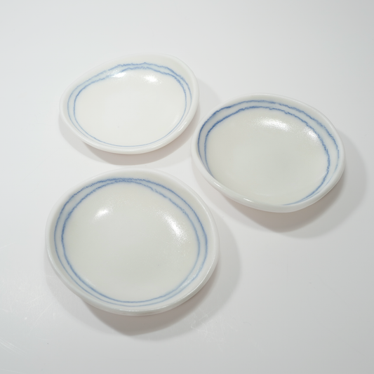 Three white ceramic dishes with blue line designs, made by Jenny Dowd