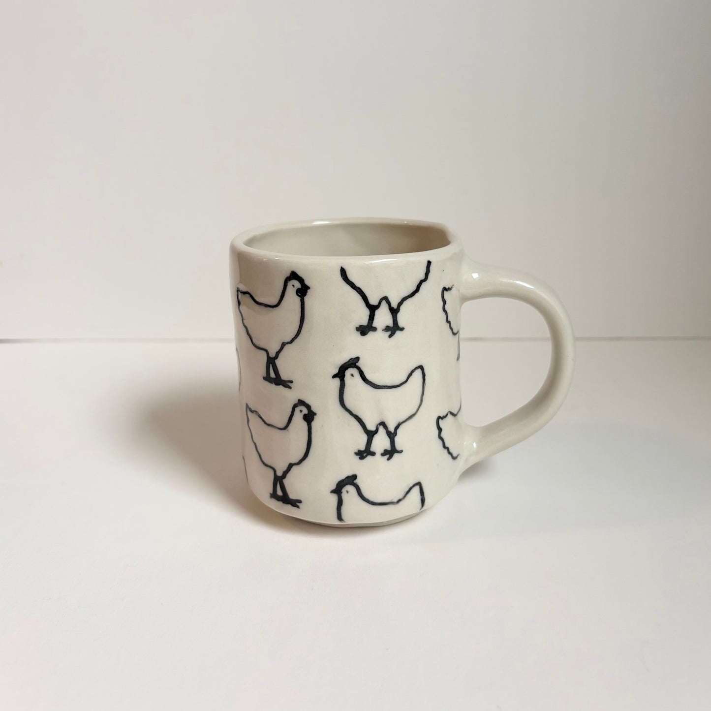 White mug with black chicken designs