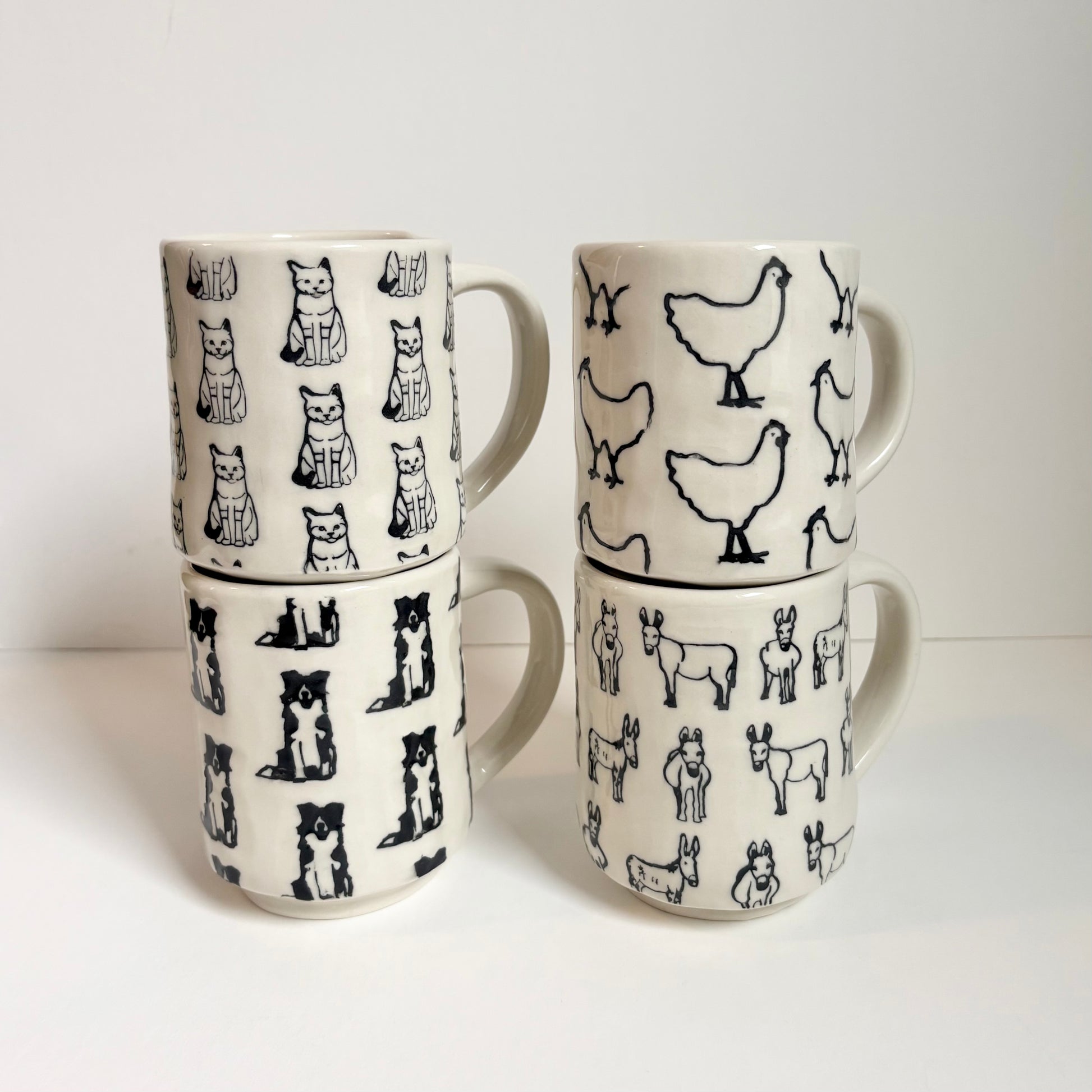 Set of four ceramic mugs with animal patterns on a white background