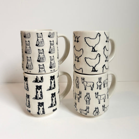 Set of four ceramic mugs with animal patterns on a white background