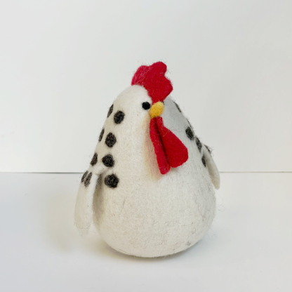White felted chicken with black spots and a red comb on a white background