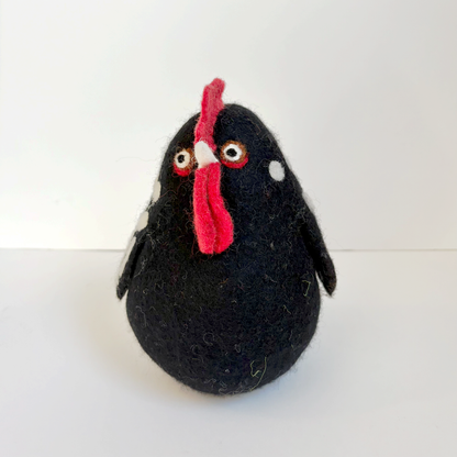 Black felted chicken with white spots and a red comb on a white background