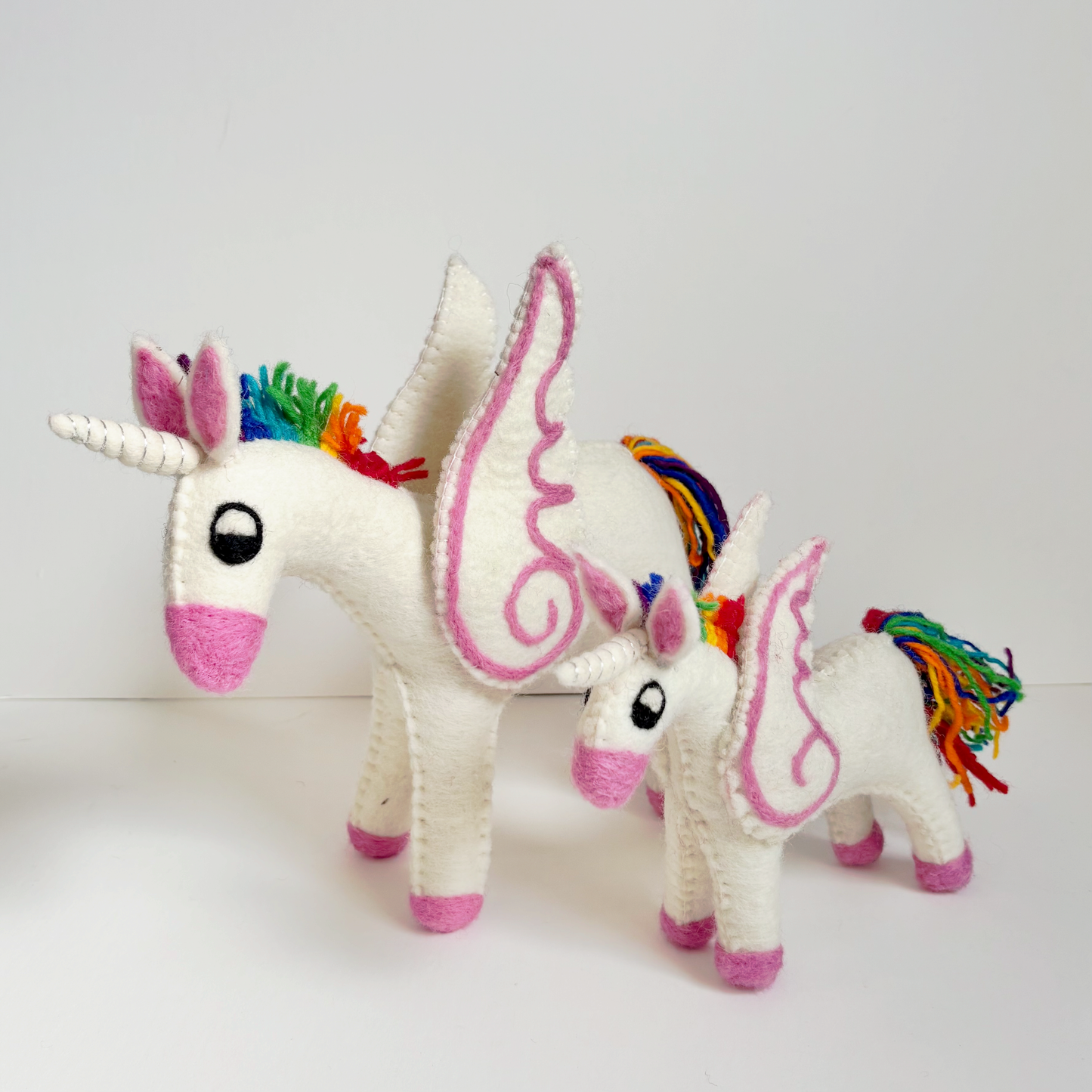 Two small unicorn toys with rainbow-colored manes on a white background