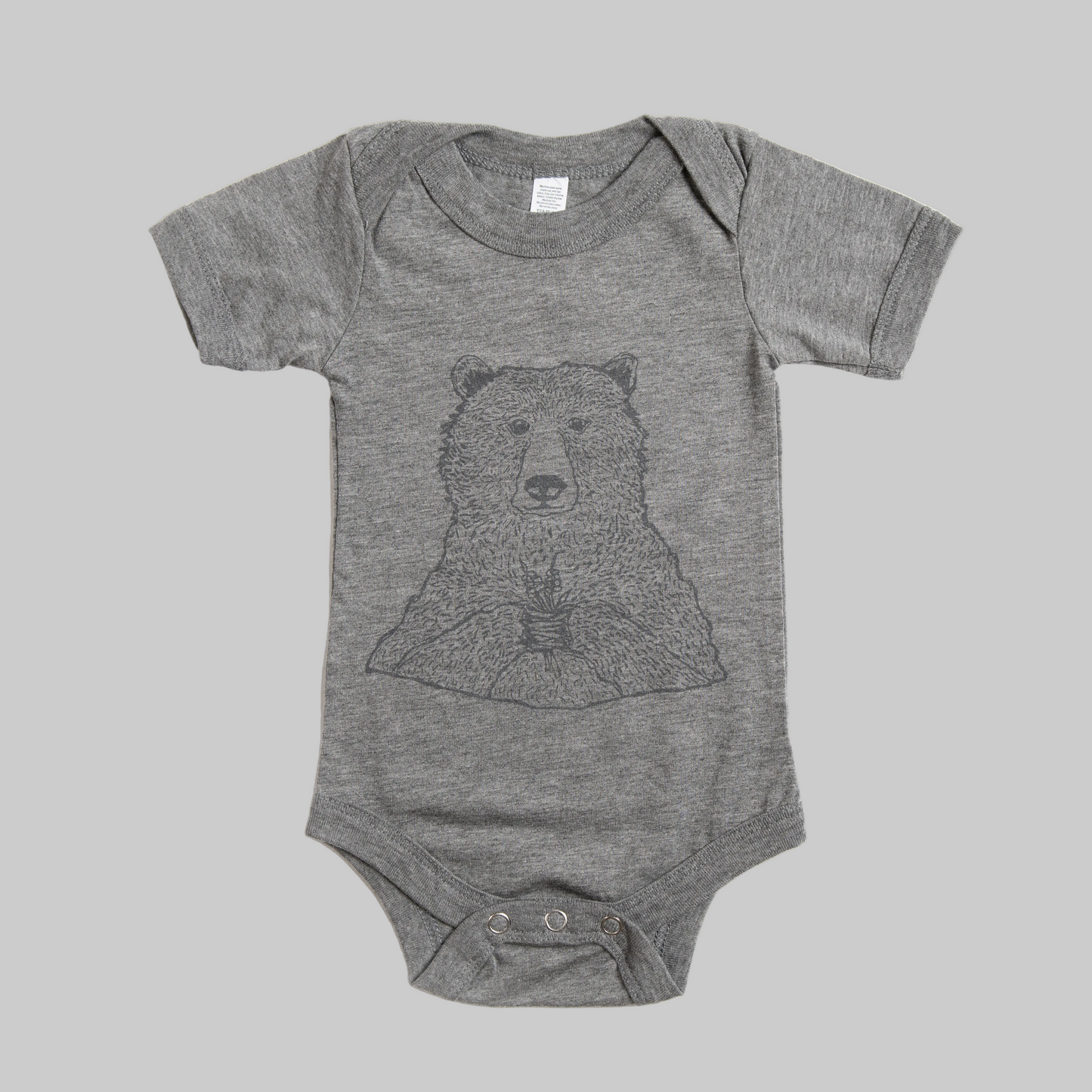 Bird and Buffalo’s baby onesie in gray with a bear holding flowers design, made locally in Jackson Hole, WY
