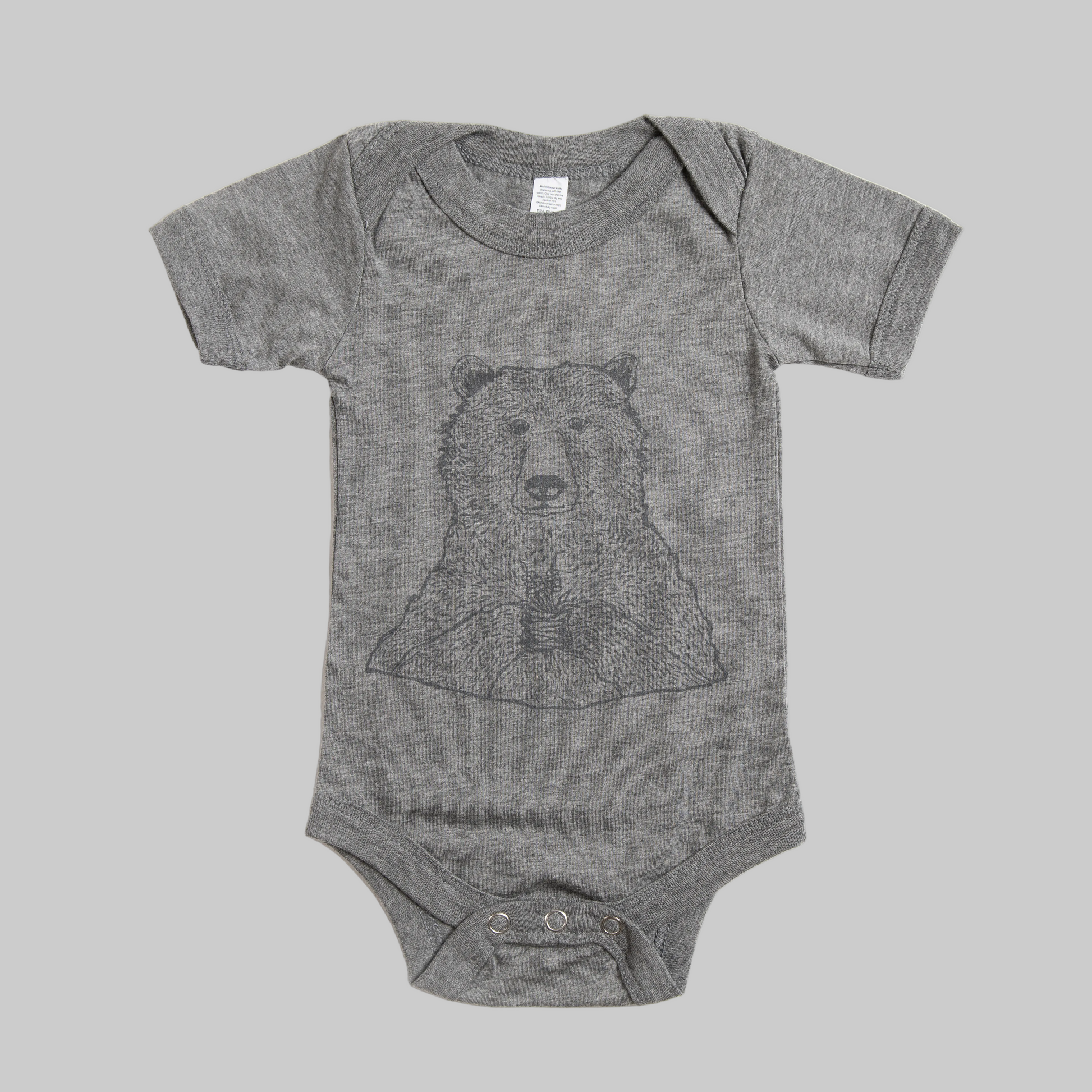 Bird and Buffalo’s baby onesie in gray with a bear holding flowers design, made locally in Jackson Hole, WY