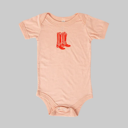 Bird and Buffalo’s baby onesie in pink with a red boots design, made locally in Jackson Hole, WY