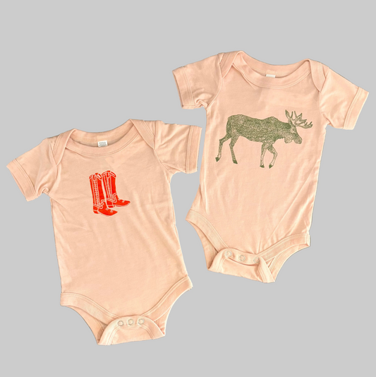 Bird and Buffalo’s baby onesie in pink with screen printed designs, made locally in Jackson Hole, WY