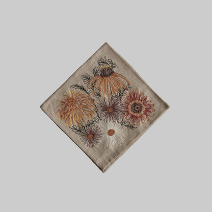 Coral and Tusk’s “Autumn Blossoms” embroidered linen dinner napkin featuring sunflowers, mums, and daisies in earthy tones