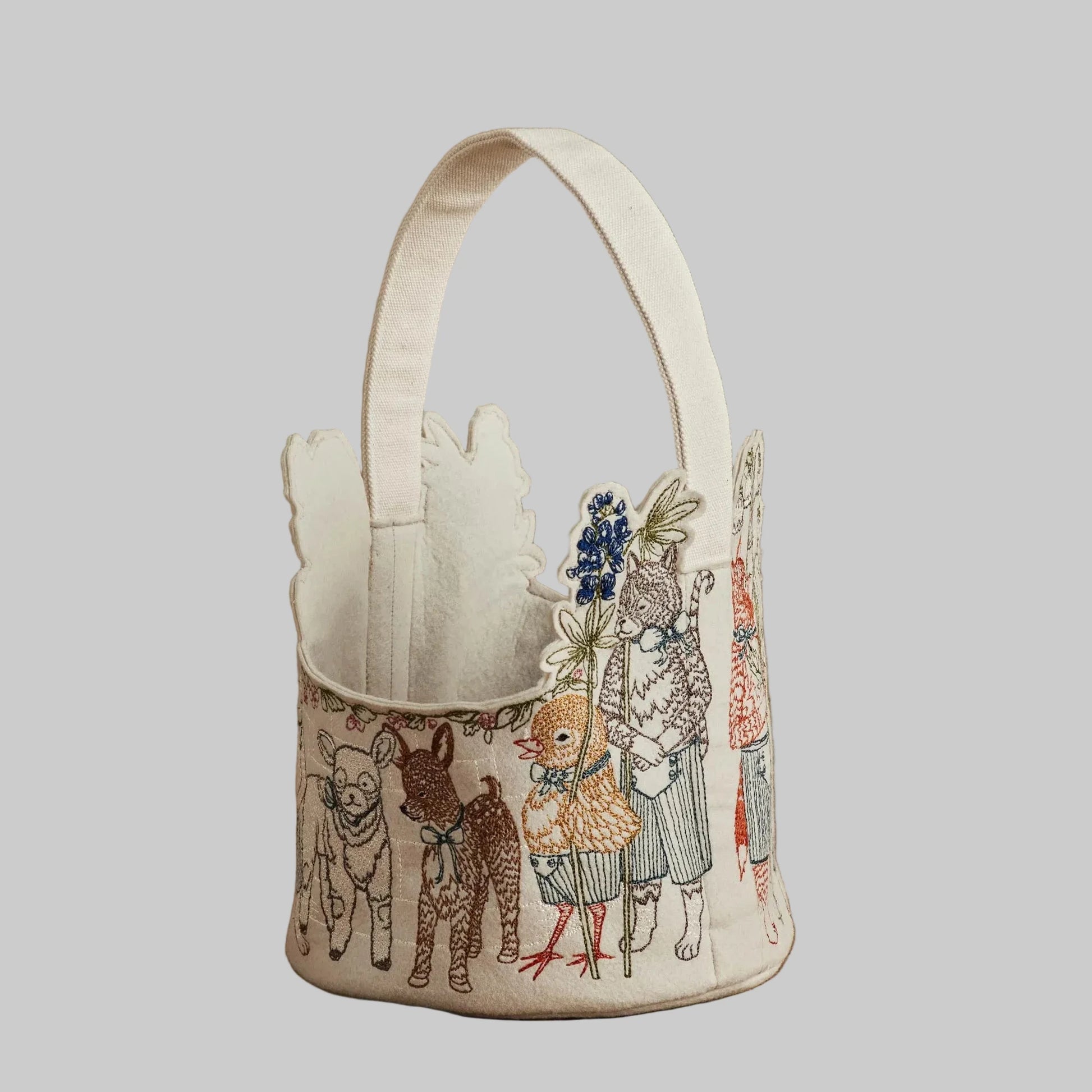 Coral and Tusk’s “Spring Parade” embroidered felt Easter basket, featuring animal friends carrying lilies and bluebonnets