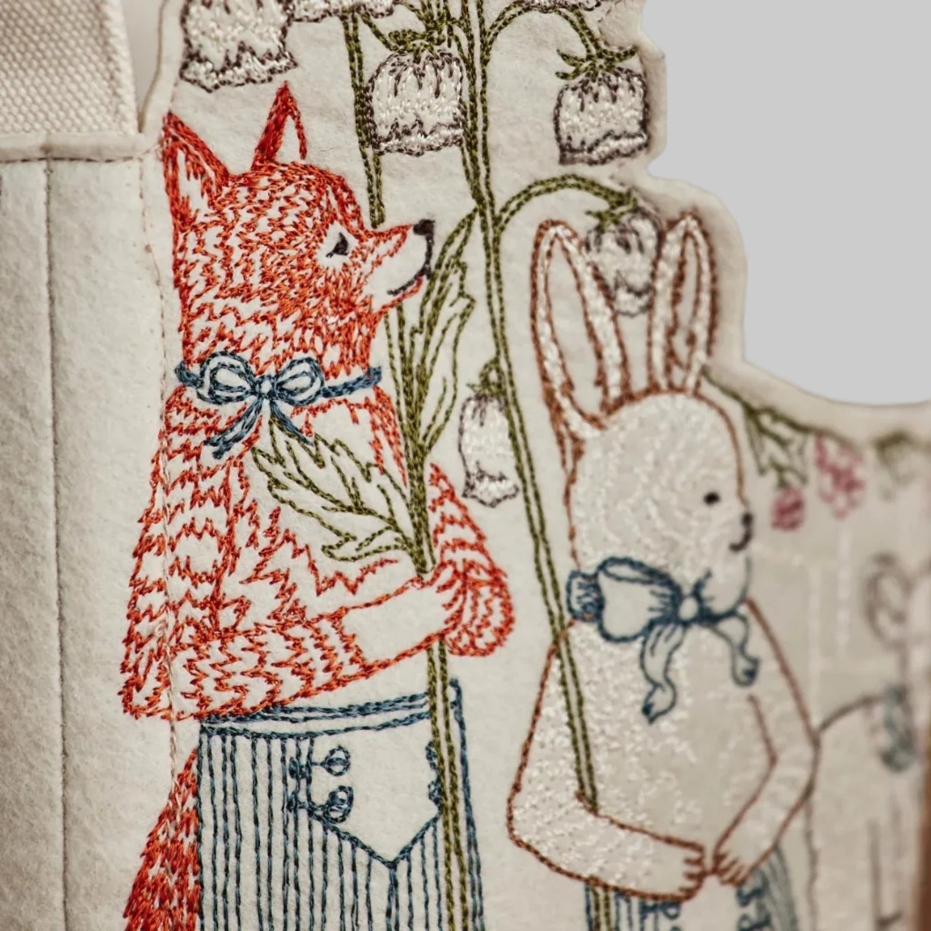 Coral and Tusk’s “Spring Parade” embroidered felt Easter basket, featuring animal friends carrying lilies and bluebonnets