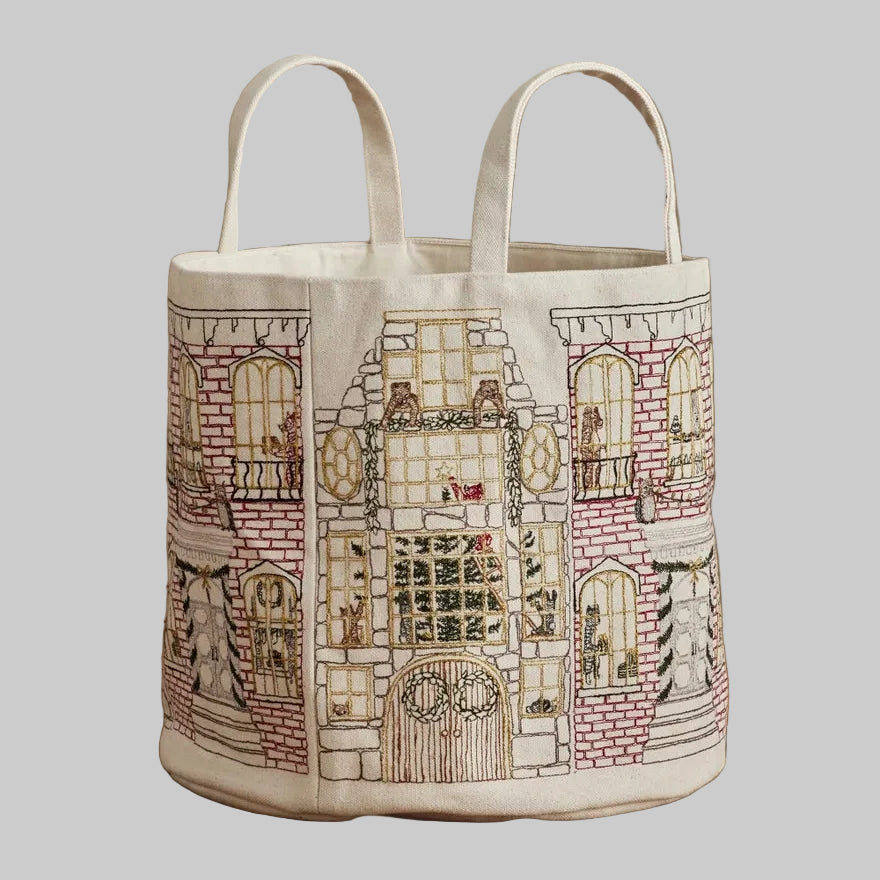 Coral and Tusk's "Home For the Holidays" embroidered canvas bucket featuring intricate designs of woodland friends decorating their city home