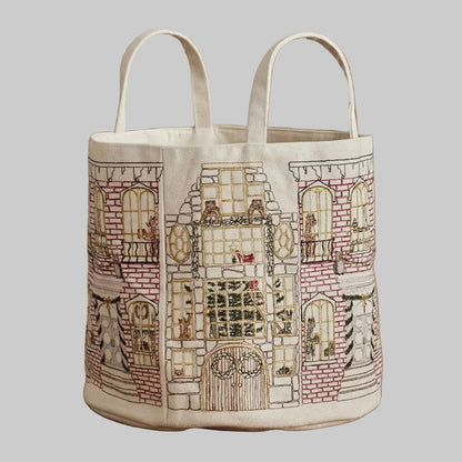 Coral and Tusk's "Home For the Holidays" embroidered canvas bucket featuring intricate designs of woodland friends decorating their city home