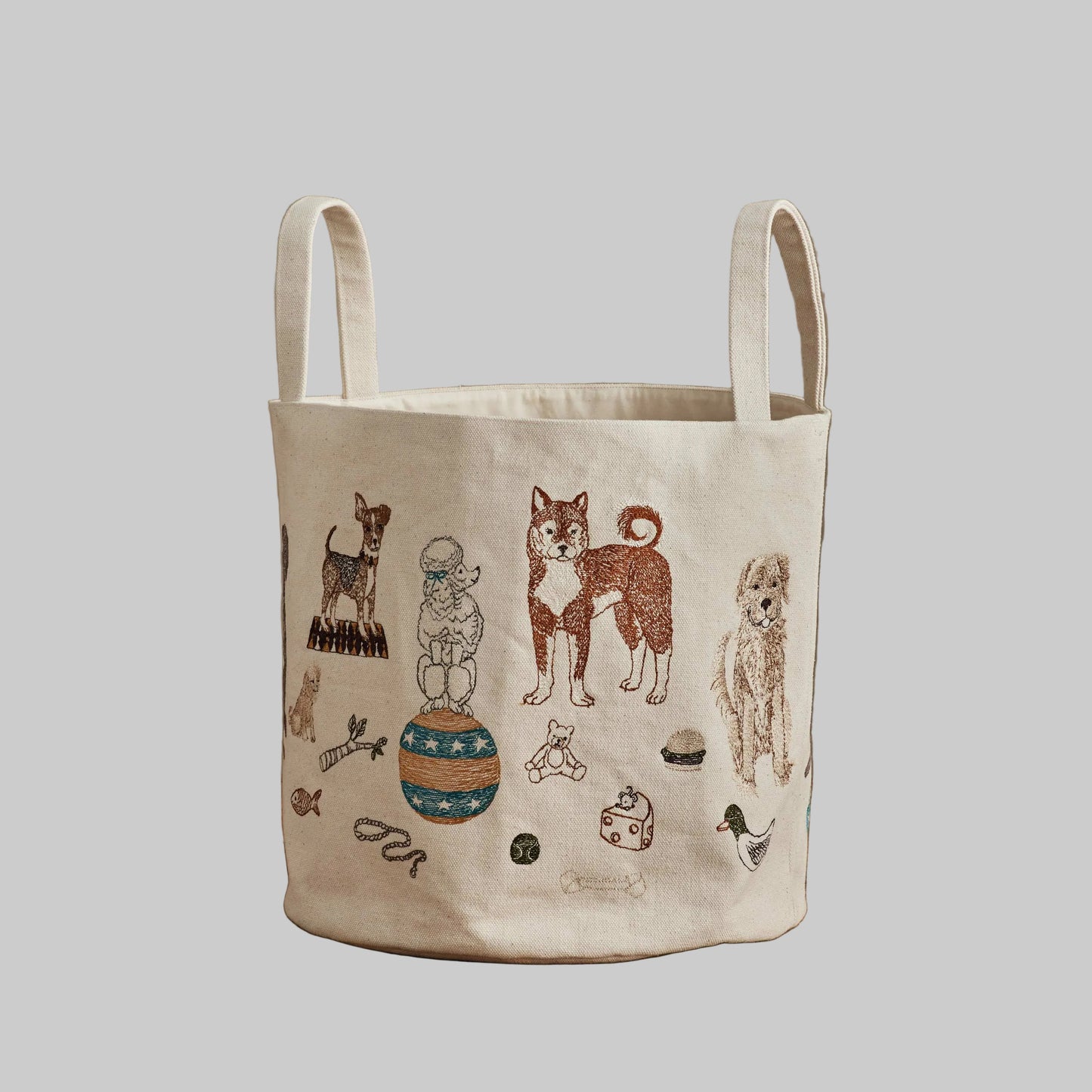 Coral and Tusk’s “Dog Toy” embroidered canvas bucket featuring designs of dogs and their toys