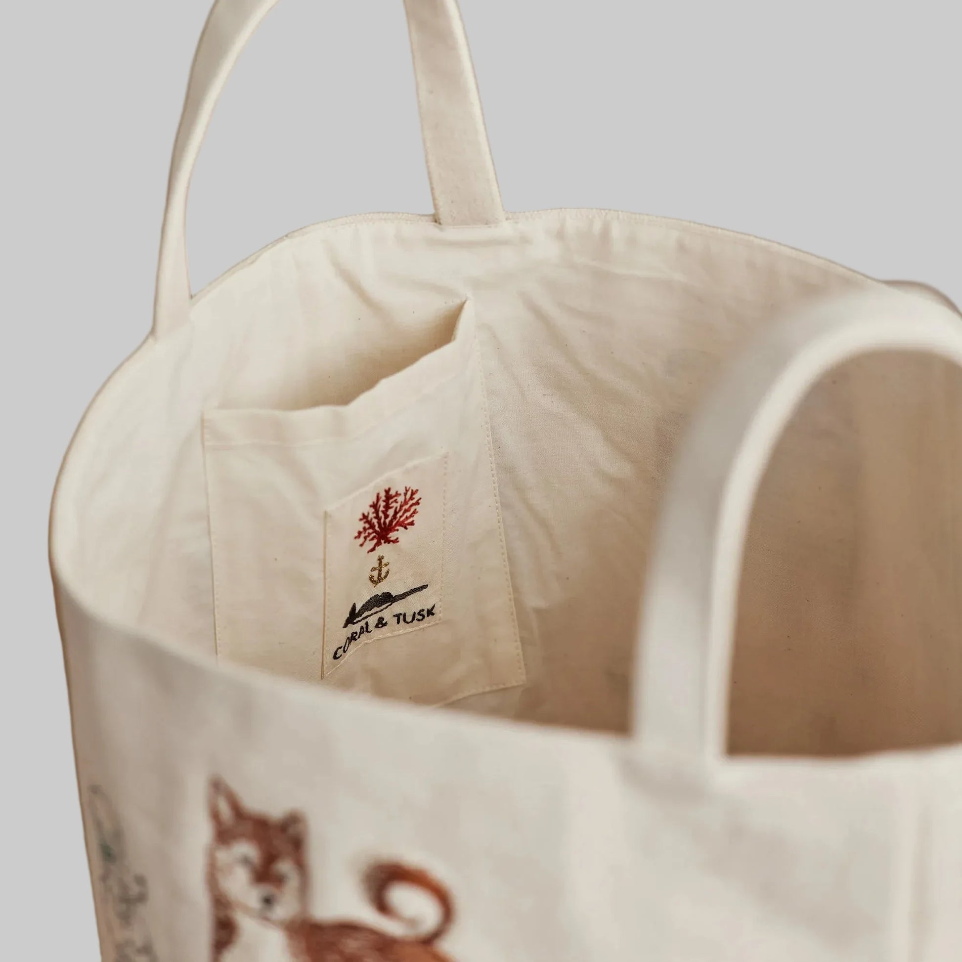 Coral and Tusk’s “Dog Toy” embroidered canvas bucket featuring designs of dogs and their toys