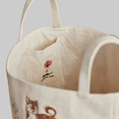 Coral and Tusk’s “Dog Toy” embroidered canvas bucket featuring designs of dogs and their toys