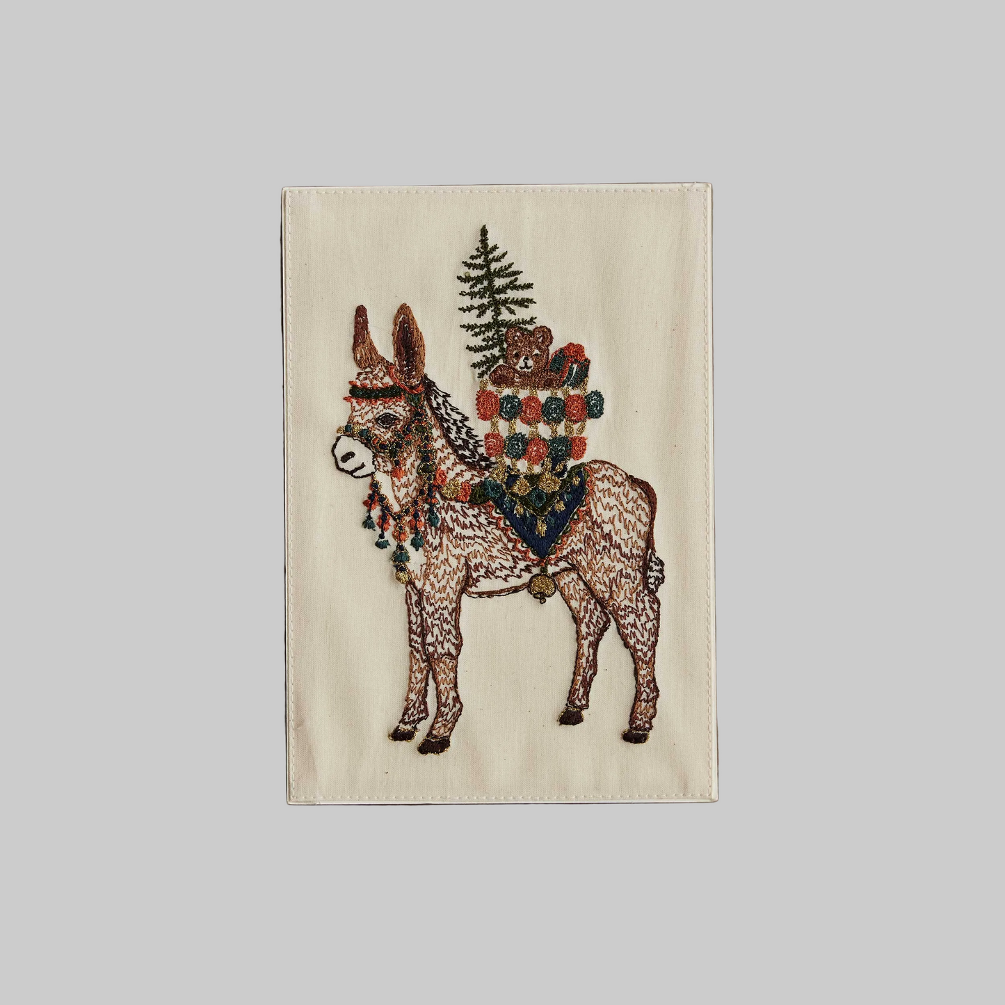 Coral and Tusk's "Christmas Donkey" embroidered keepsake card  featuring a festive donkey carrying gifts on its back