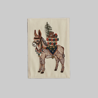 Coral and Tusk's "Christmas Donkey" embroidered keepsake card  featuring a festive donkey carrying gifts on its back