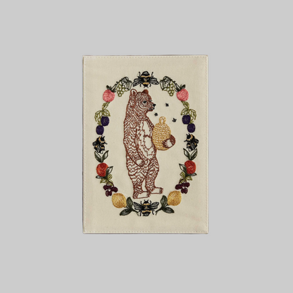 Coral and Tusk's "Honey Bear" embroidered keepsake card  featuring a bear holding a beehive surrounded by a wreath of fruits