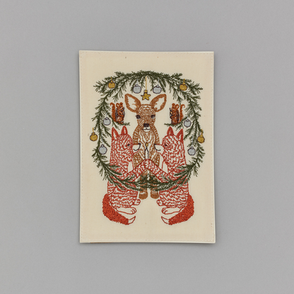 Coral and Tusk's "Togetherness" embroidered keepsake card  featuring foxes, chipmunks, and a deer surrounded by a holiday wreath
