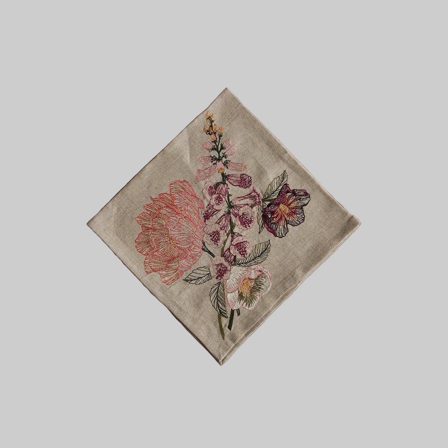 Coral and Tusk’s “Blush Bouquet” embroidered linen dinner napkin featuring vibrant florals in shades of pink and maroon