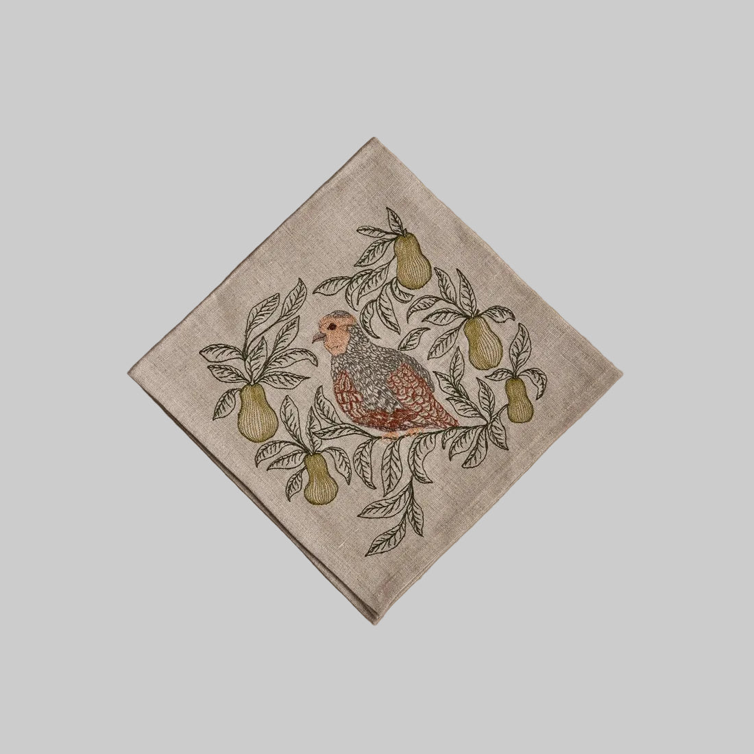 Coral and Tusk’s “Partridge in a Pear Tree” embroidered linen dinner napkin featuring a small partridge surrounded by pears and leaves