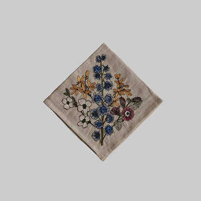 Coral and Tusk’s “Spring Stems” embroidered linen dinner napkin featuring a bouquet of blue, yellow, pink, and white florals