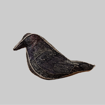 Coral and Tusk's Blackbird of Mystery keepsake object featuring detailed embroidery in black, indigo, violet, and maroon