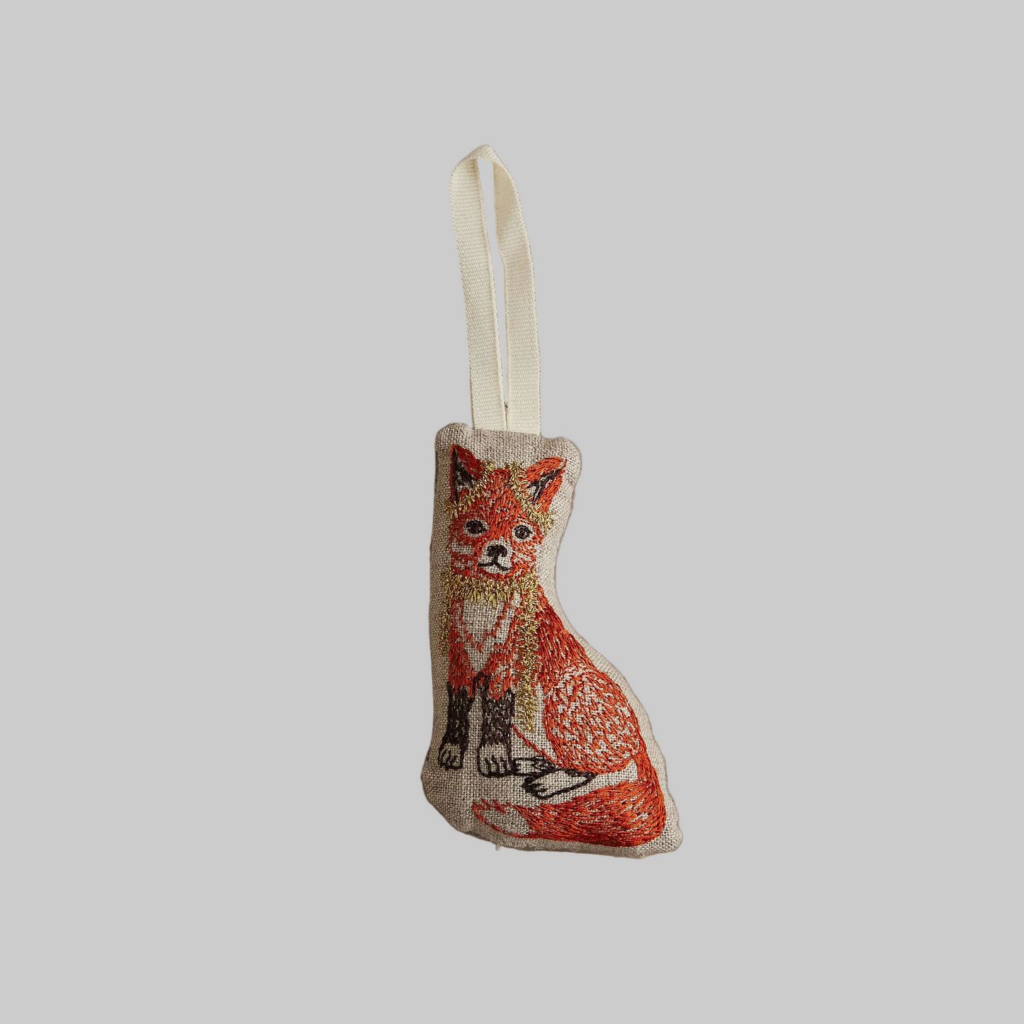 Coral and Tusk's "Fox Tree Trimmer" embroidered linen Christmas ornament featuring design of a fox wearing a gold tinsel necklace