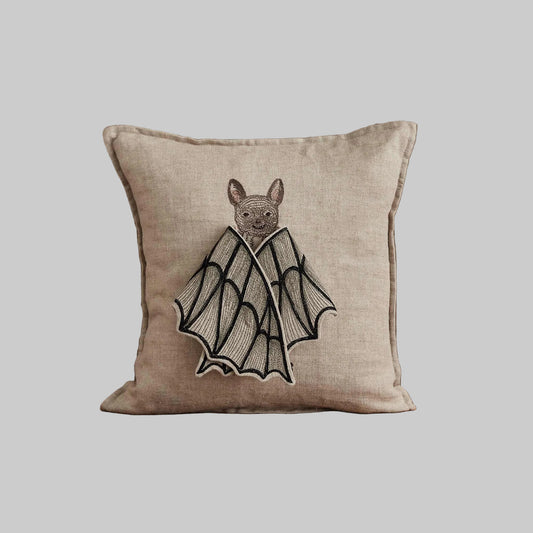 Coral and Tusk’s “Bat Wing Surprise” embroidered linen pillow featuring a bat with wings that open up to reveal the design of a butterfly, measures 12x12