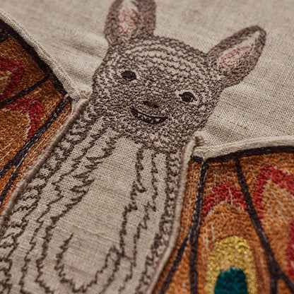 Coral and Tusk’s “Bat Wing Surprise” embroidered linen pillow featuring a bat with wings that open up to reveal the design of a butterfly, measures 12x12