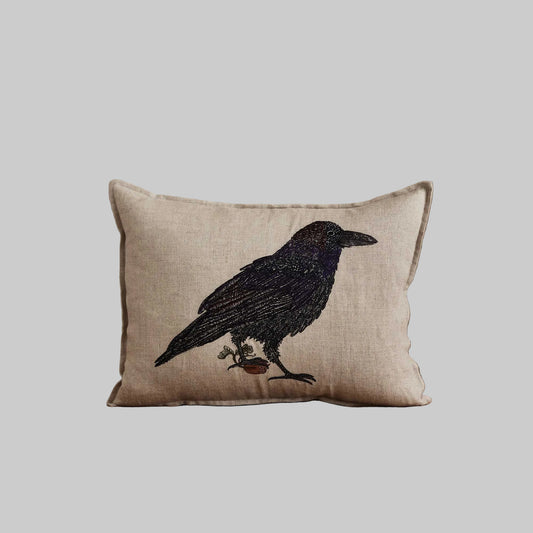 Coral and Tusk’s “Blackbird with Acorn” embroidered linen pillow featuring a blackbird holding an acorn in its claw, measures 12” x 16”