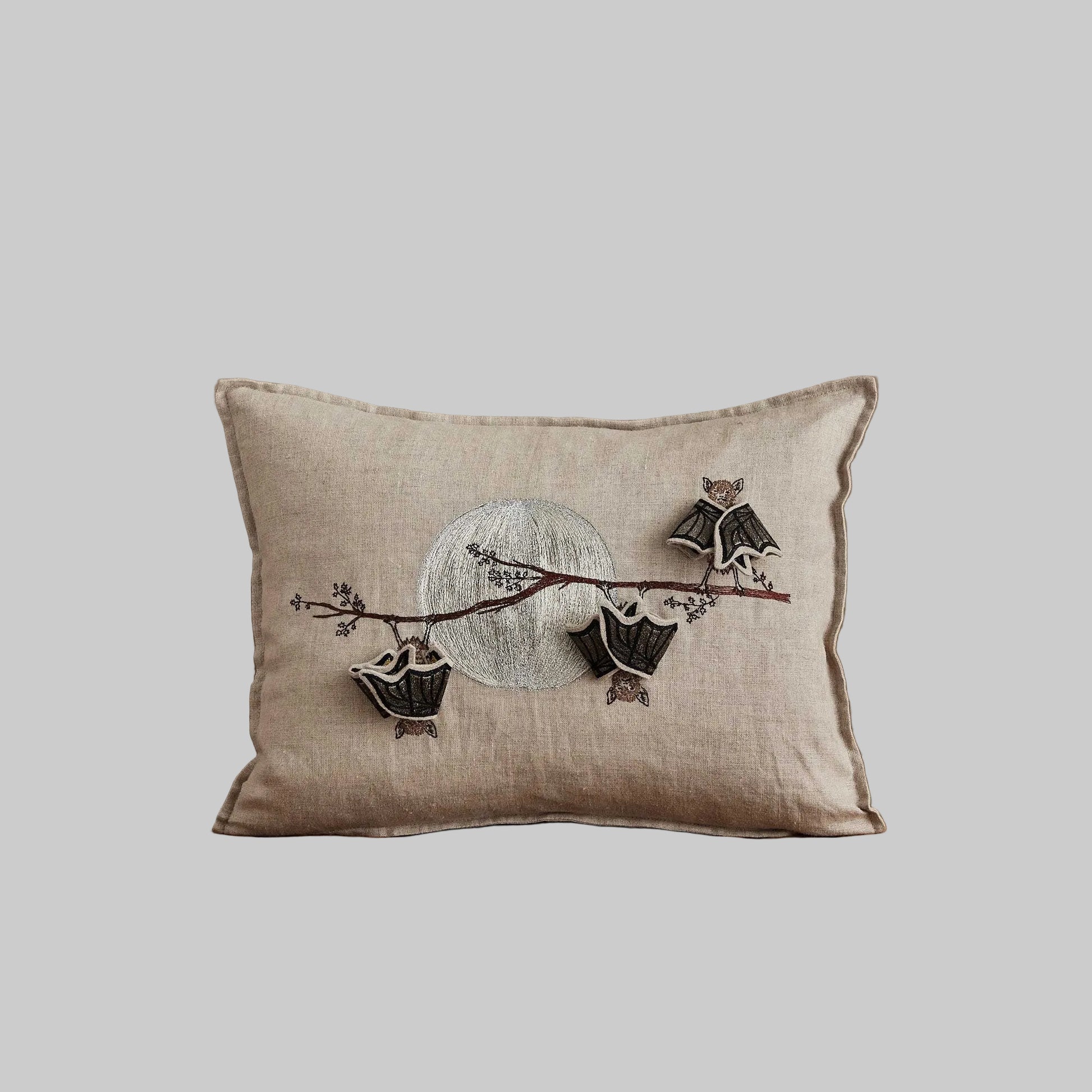 Coral and Tusk’s “Bat Branch” embroidered linen pillow featuring three bats hanging from a maple tree branch