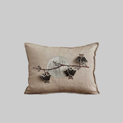 Coral and Tusk’s “Bat Branch” embroidered linen pillow featuring three bats hanging from a maple tree branch