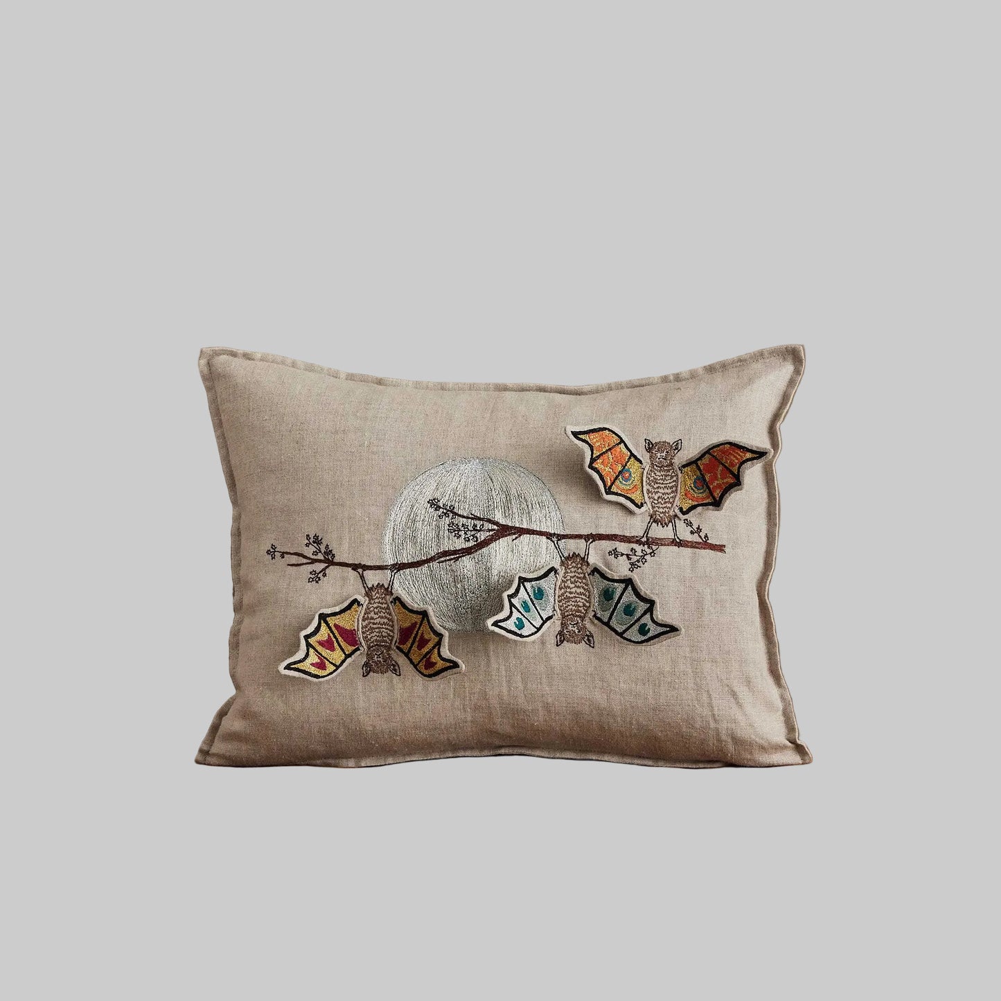 Coral and Tusk’s “Bat Branch” embroidered linen pillow featuring three bats hanging from a maple tree branch