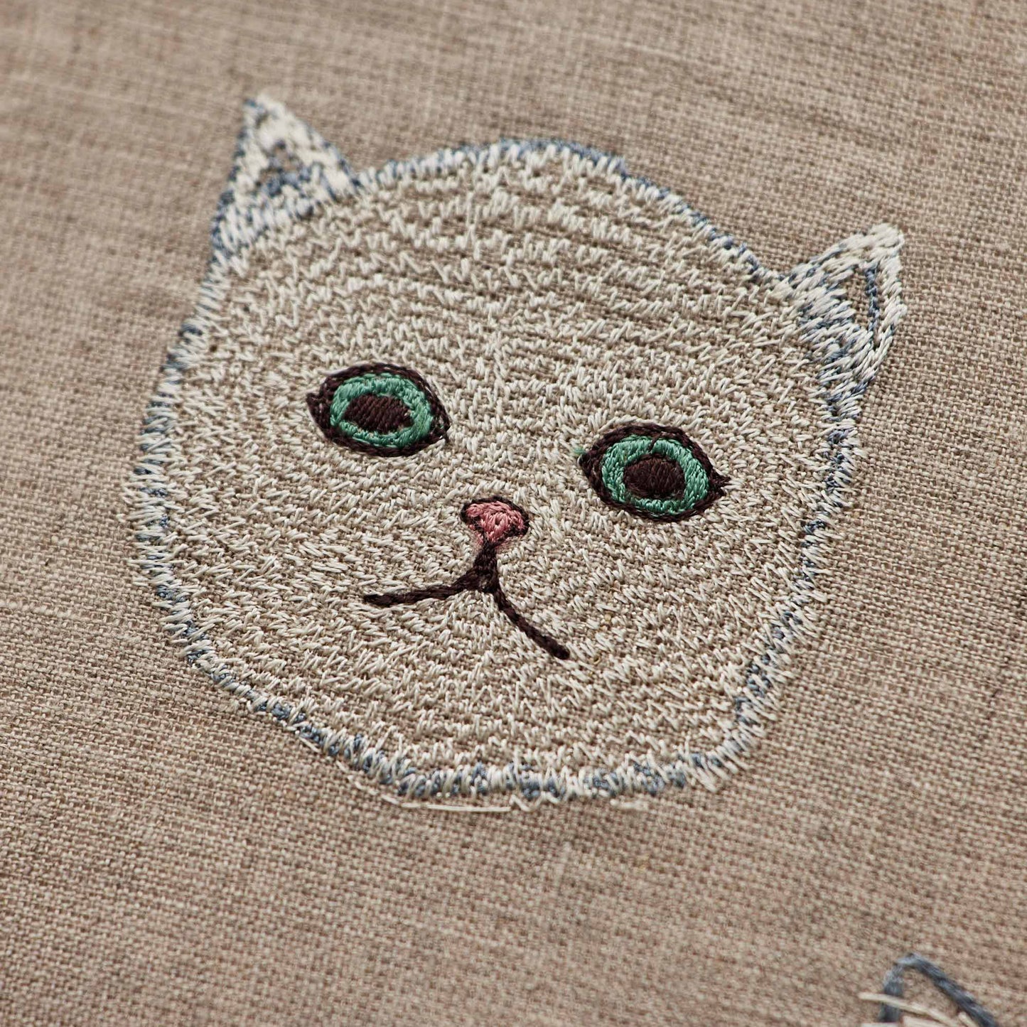 Coral and Tusk’s “Charming Cats” embroidered linen pillow featuring five cats and their lucky charms, measures 12” x 12”