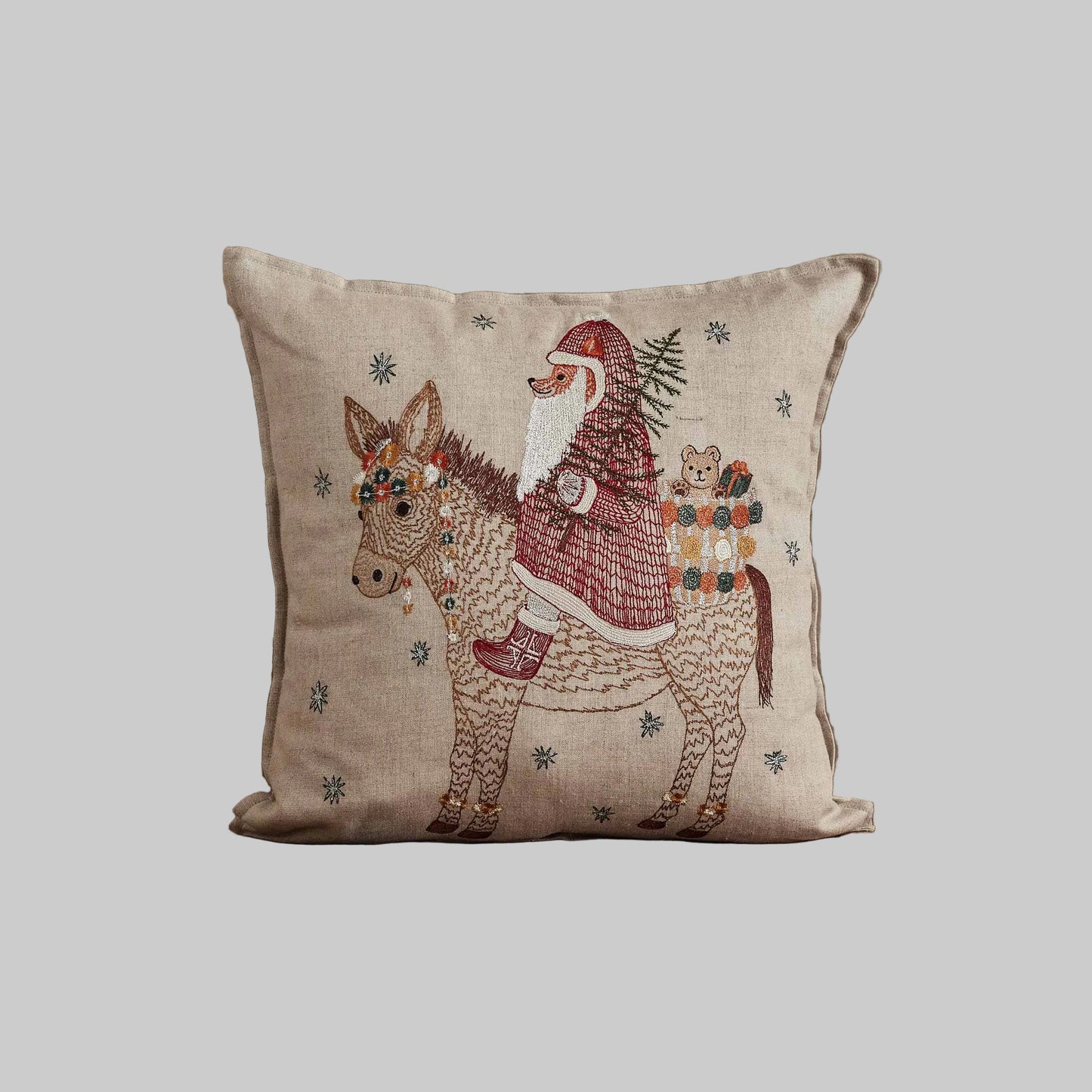 Coral and Tusk’s “Christmas Donkey” embroidered linen pillow featuring a  fox dressed up as Santa riding in on a festively-adorned donkey, measures 16” x 16”