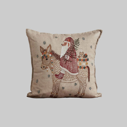 Coral and Tusk’s “Christmas Donkey” embroidered linen pillow featuring a  fox dressed up as Santa riding in on a festively-adorned donkey, measures 16” x 16”