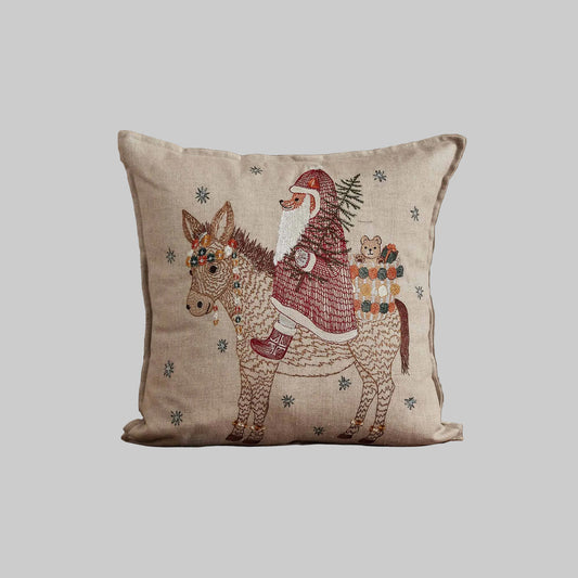 Coral and Tusk’s “Christmas Donkey” embroidered linen pillow featuring a  fox dressed up as Santa riding in on a festively-adorned donkey, measures 16” x 16”