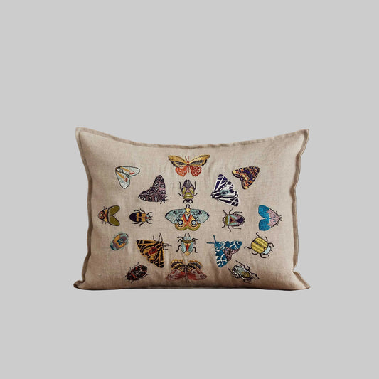 Coral and Tusk’s “Fancy Flight” embroidered linen pillow featuring colorful depictions of moths and beetles, measures 12” x 16”