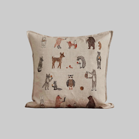 Coral and Tusk’s “Woodland Friends” embroidered linen pillow featuring woodland creature pals and their foraged finds, measures 20” x 20”