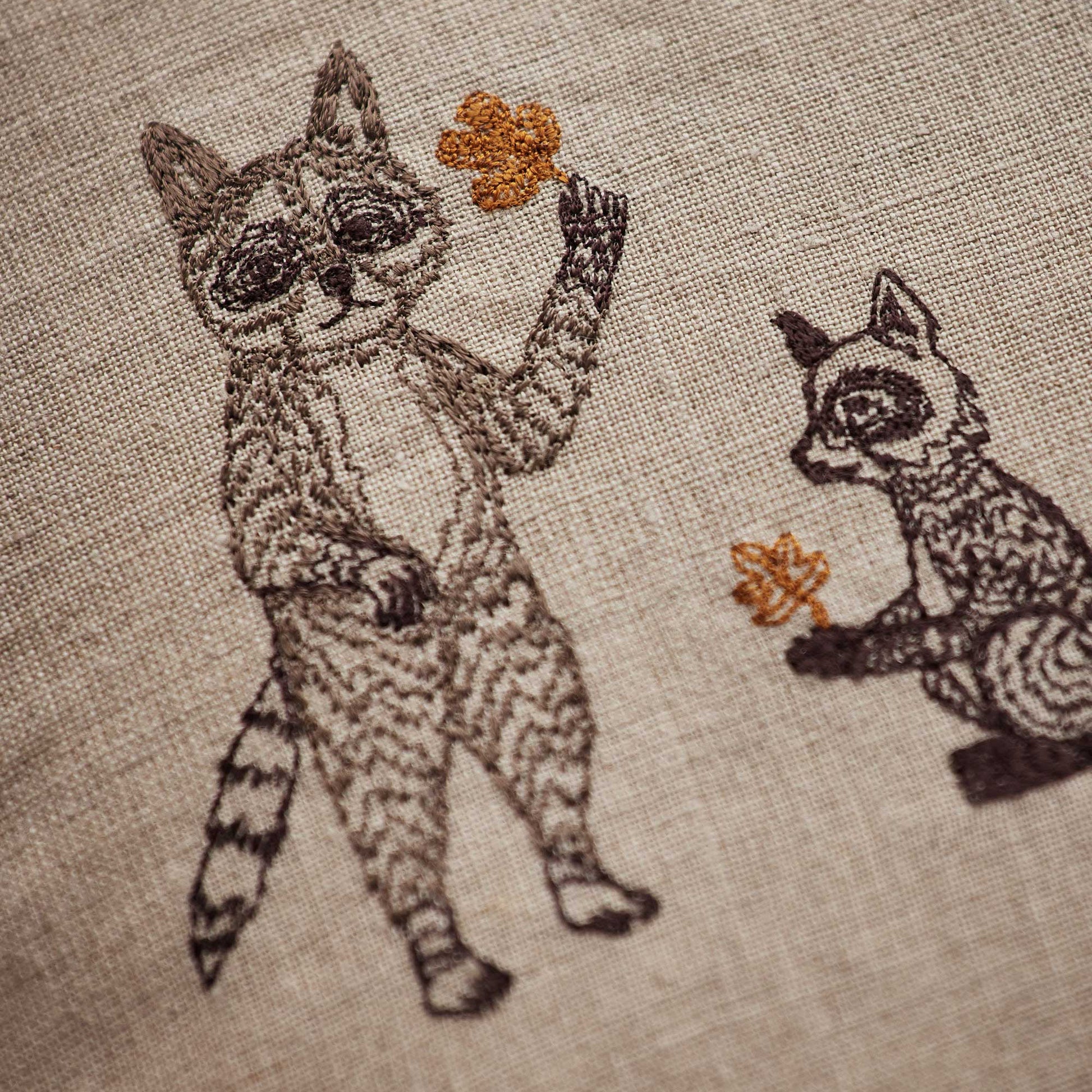 Coral and Tusk’s “Woodland Friends” embroidered linen pillow featuring woodland creature pals and their foraged finds, measures 20” x 20”