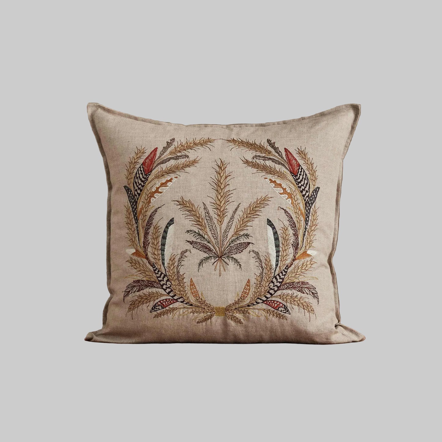 Coral and Tusk’s “Wheat Harvest” embroidered linen pillow featuring a wreath of wild grasses, grains, stalks of wheat, and found feathers, measures 20” x 20”